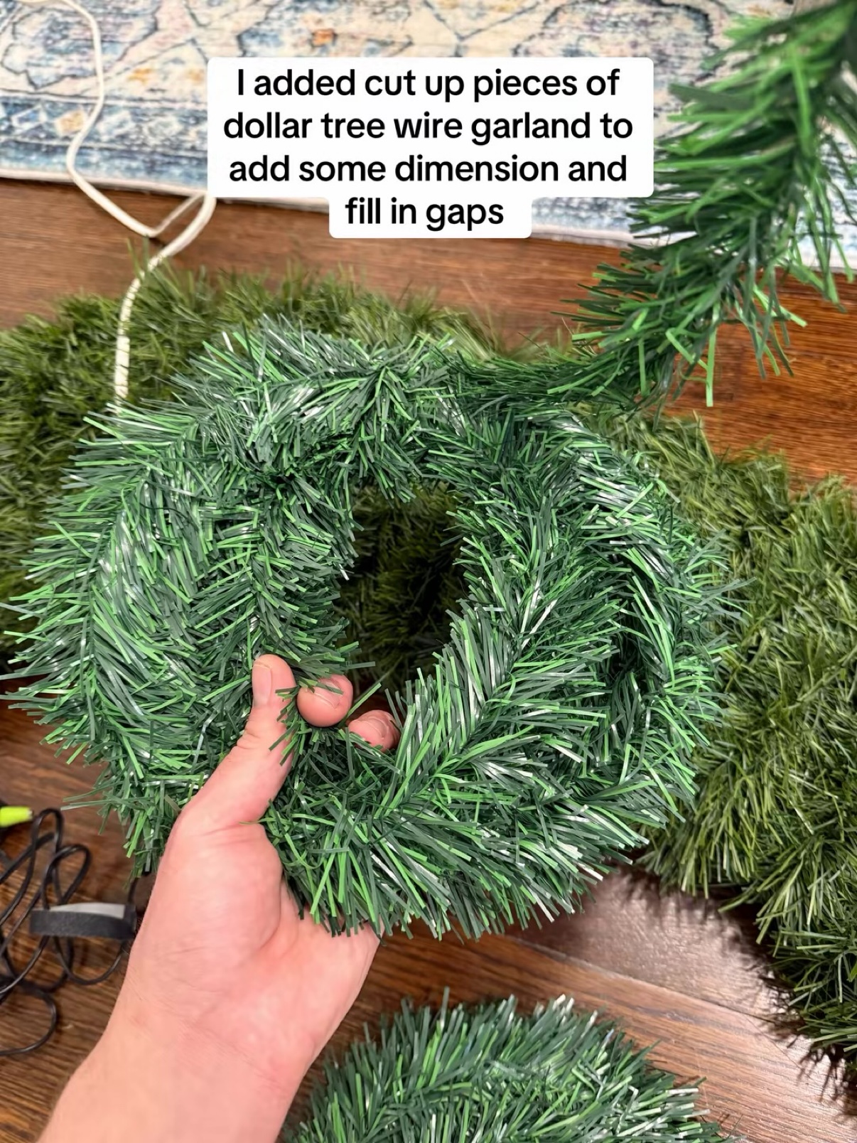 Hand holding a piece of Dollar Tree wire garland against the wreath