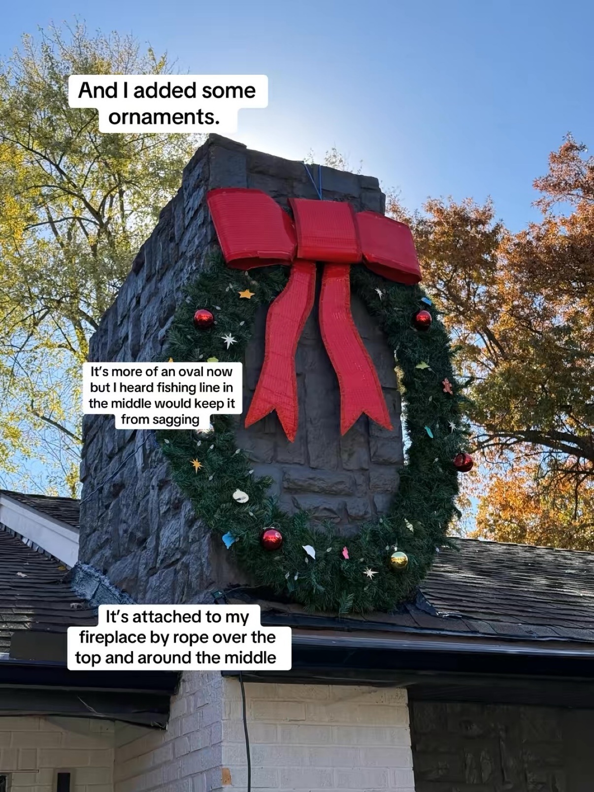 Giant wreath with red bow and ornaments hanging on the fireplace