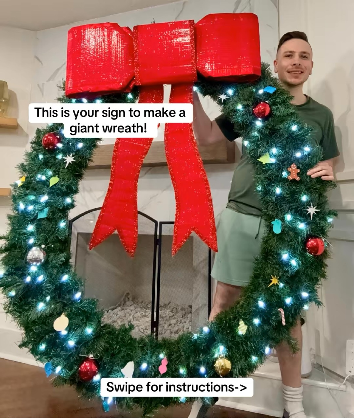 Ryan holding a giant Christmas wreath with a big red bow